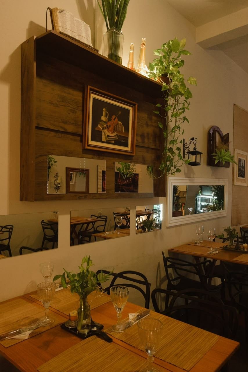 Salão com mesas de madeira, plantas e quadros decorativos
